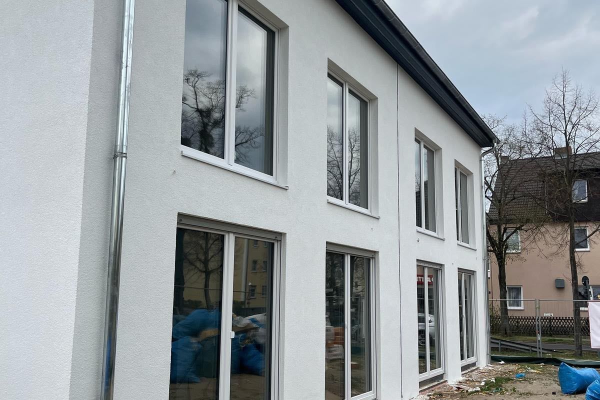 Neubau mit heller Putzfassade und großen bodentiefen Fenstern