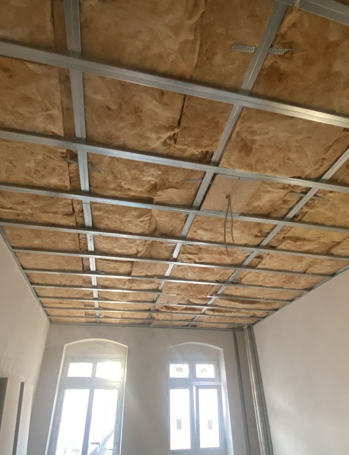 Altbauraum mit Rundbogenfenstern und neuer gedämmter Deckenunterkonstruktion