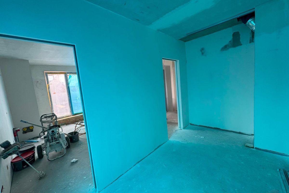 Wohnung im Umbau mit frisch grundierten Wänden und Werkzeug auf dem Boden